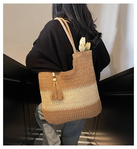 Detail of tri-color woven straw tote bag featuring tassel charms and hemp rope handles