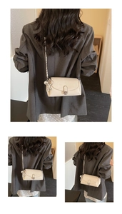 Détail du sac baguette crème avec boucle argentée et charm chien sur un blazer gris