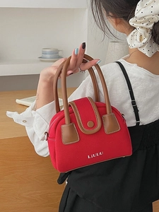 Red canvas boston bag with brown leather handles and brand logo shown in hand
