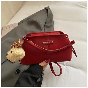 Detail of dark red crossbody bag with soft matte texture and cute bear charm accent