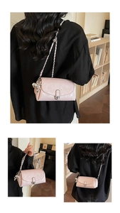 Détail du sac baguette en cuir rose clair avec bandoulière chaîne et breloque lapin