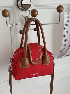 Red canvas square handbag with brown leather trim and white LIVUU embroidery on a hook