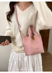 Sac seau rose en cuir grainé avec fermoir rotatif doré et bandoulière amovible