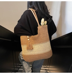 Detail of woven straw tote bag featuring brown and beige stripes with tassel and tulips