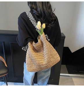 Detail of woven straw shoulder bag featuring textured pattern and striped fabric strap