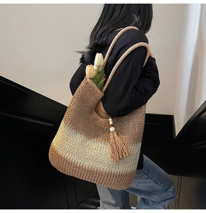 Detail of woven straw tote bag with gradient tones, wooden beads, and a large tassel charm