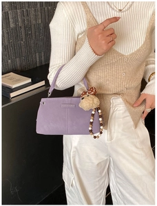 Lavender crossbody bag with round handle and plush dot charm shown on model