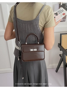Elegante Frau mit dunkelbrauner Vintage-Umhängetasche neben einem Korbstuhl