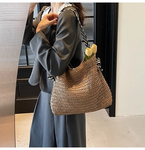Detail of woven straw shoulder bag featuring a decorative striped silk scarf handle wrap