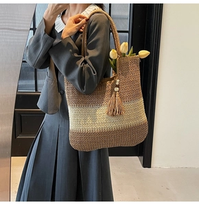 Detail of hand-woven straw tote bag with gradient colors and decorative wooden bead tassel