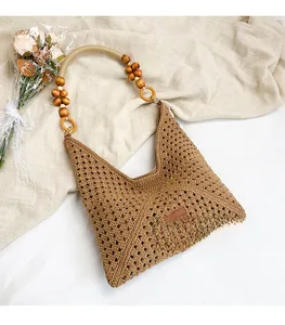 Close-up of brown crochet woven tote bag with designer wooden bead handle and logo tag