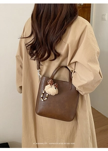 Détail du sac cabas marron foncé avec breloque ours en peluche et lanière en perles