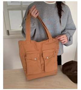 Detail der orangebraunen Canvas-Einkaufstasche mit zwei Vordertaschen und Metallschnallen