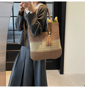 Detail of handwoven gradient straw tote bag with decorative wooden bead tassels