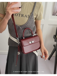 Detail einer burgunderroten Vintage-Ledertasche mit metallischem Drehverschluss