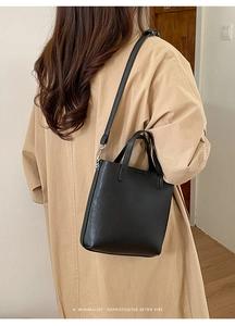 Vue détaillée du sac cabas en cuir noir porté avec un trench pour un look rétro