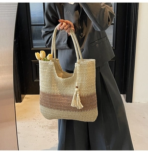 Detail of woven straw tote bag with contrast stripes and decorative tassel