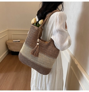Detail of a large straw tote bag with wave pattern, beaded tassels and wide shoulder strap