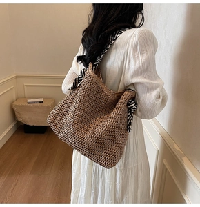 Detail of woven straw tote bag with black and white striped scarf wrapped around handle