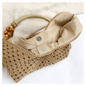 Close-up of woven tote bag showing wooden bead handle and magnetic clasp detail