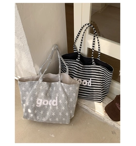 Detail of canvas tote bags featuring bold 'good' lettering and striped patterns