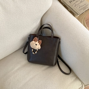 Détail du sac fourre-tout en cuir mat marron foncé avec pendentif ours mignon