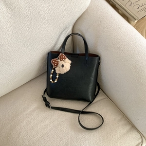 Détail d'un sac à main en cuir noir avec un ours en peluche et des perles de bois