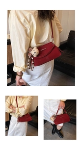 Detail of red crossbody bag with plush bear charm and beaded strap on leather sofa