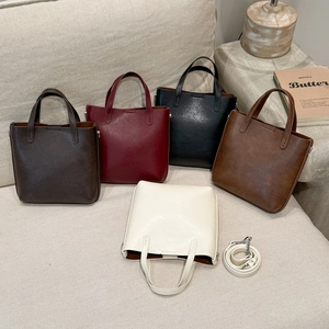 Détail de cinq sacs cabas rétro multicolores avec bandoulière amovible sur un canapé