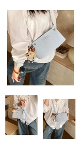 Close-up of light blue crossbody bag with bear charm and bow detail shown on a model
