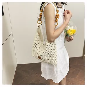 Detail of hollow woven tote bag featuring decorative wooden beads and a leather logo patch