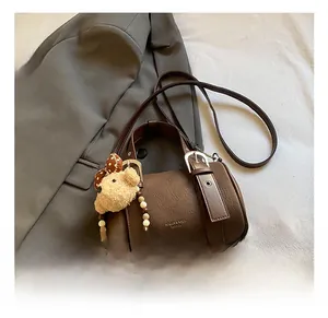Detail of dark brown cylinder pillow bag with lychee texture and cute bear charm