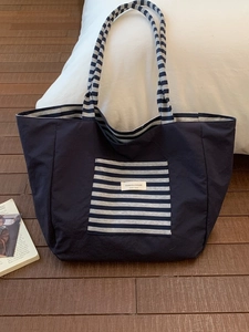 Large navy canvas tote bag with striped straps and front pocket for college students
