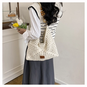 Close-up of beige hollow knit tote bag featuring decorative wooden bead handles