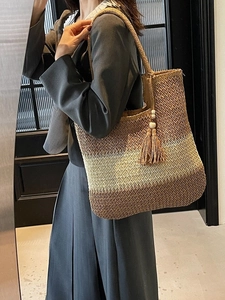 Large woven straw tote bag with brown gradient stripes and bohemian tassel detail