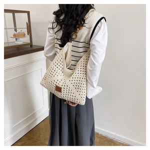 Detail of hollow woven tote bag with wooden bead straps and brown leather patch