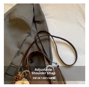 Detail of adjustable strap and litchi texture on brown leather crossbody pillow bag