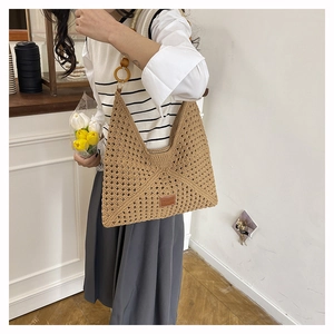 Detail of hollow woven tote bag featuring round wooden handles and premium leather label