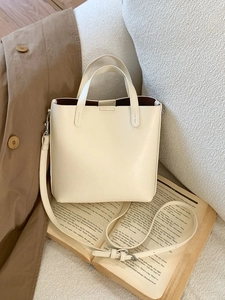 Sac fourre-tout chic en cuir beige avec bandoulière sur un trench et un livre