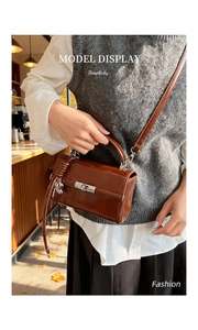 Detail einer dunkelbraunen Lackledertasche mit Silberverschluss und Pferdeanhänger
