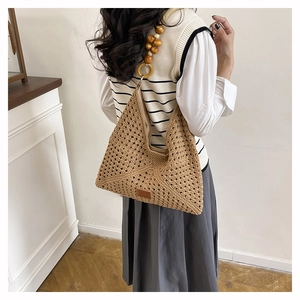 Detail of hand-woven tote bag featuring wooden bead shoulder strap and leather logo patch