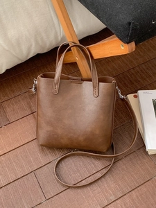 Sac à main rétro en cuir mat marron foncé avec bandoulière réglable sur parquet