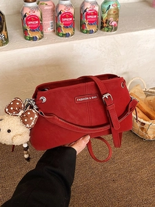 Deep red crossbody bag with plush bear charm and fashion nameplate in vintage setting