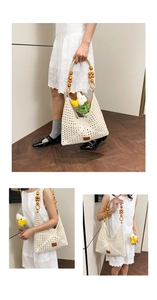 Detailed close-up of woven hollow-out beige tote bag with wooden bead handle and logo