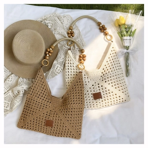 Detail view of woven beach tote bags with wooden bead handles on a summer meadow
