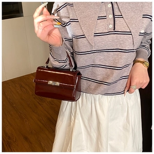 Detail of dark brown patent leather mini square bag with silver metal swivel lock clasp