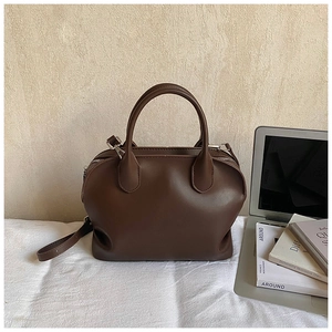 Detail of a dark brown matte leather Boston bag with silver hardware and adjustable strap