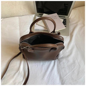 Detailed view of the open brown shell bag showing black inner lining and spacious interior