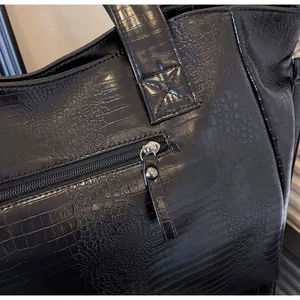 Detail of exterior zipper pocket and black crocodile pattern texture on tote bag