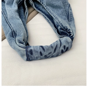Detail shot of washed blue denim headband with twill texture and twisted knot design